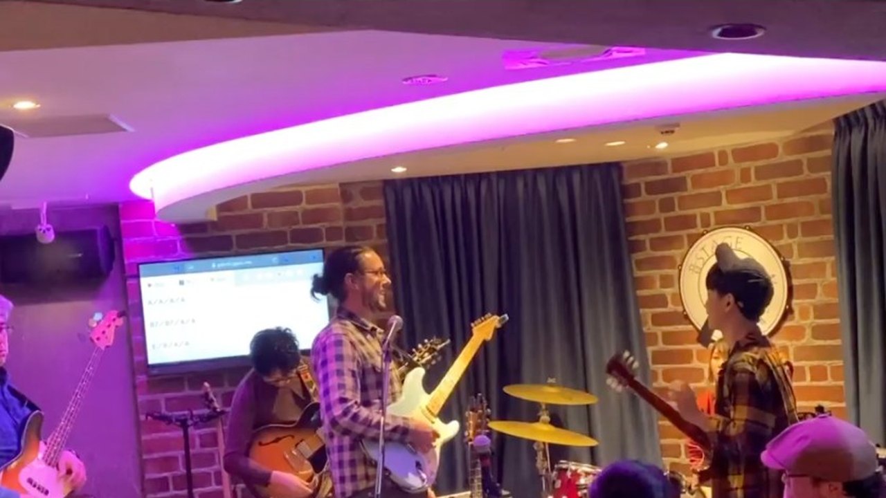 Jam session in Kanda, Tokyo: a band on a small stage under purple light, audience in front.