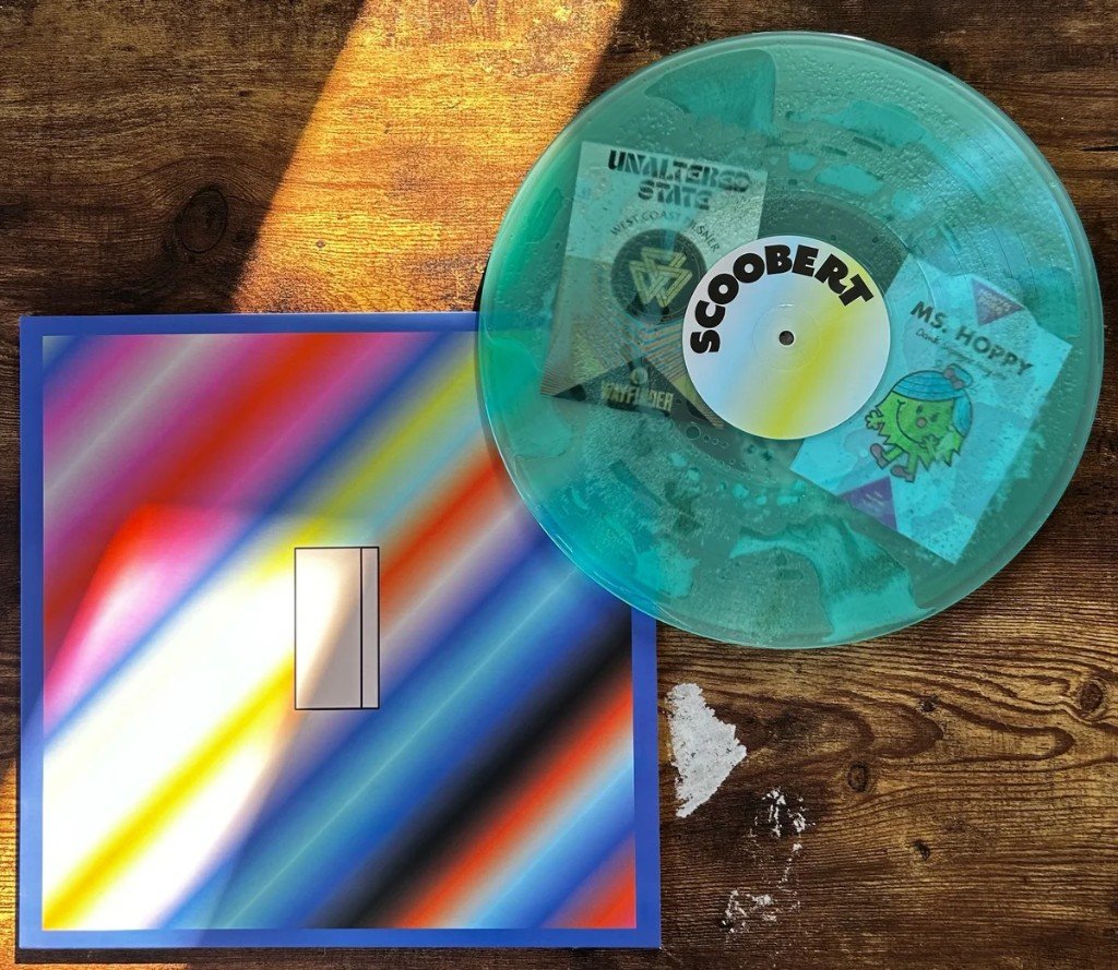 A translucent teal vinyl on the I sleeve. The label reads SCOOBERT. Beer-label stickers on the disc include Unaltered State West Coast Pilsner, Wayfinder, and Ms. Hoppy. Sand is on the table.